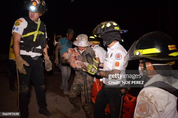 Volunteer firefighter carries a child after the eruption of the Fuego Volcano, in El Rodeo village, Escuintla department, 35 km south of Guatemala...