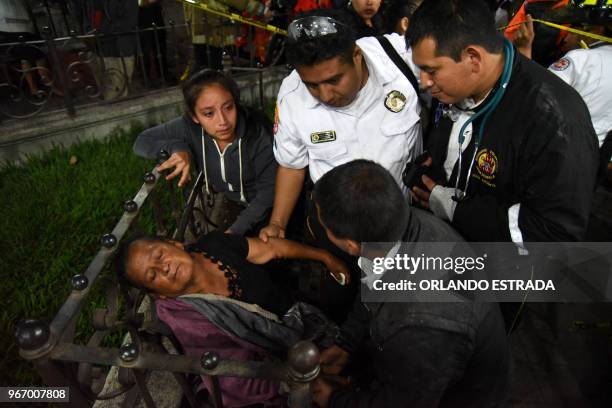 Graphic content / A woman is attended by firefighters after hearing a relative is among the victim's bodies at a morgue in Alotenango municipality,...