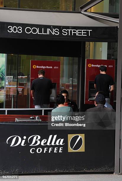 Customers use automated teller machines at a Bendigo Bank branch located behind a pavement cafe on Collins Street, in Melbourne's central business...