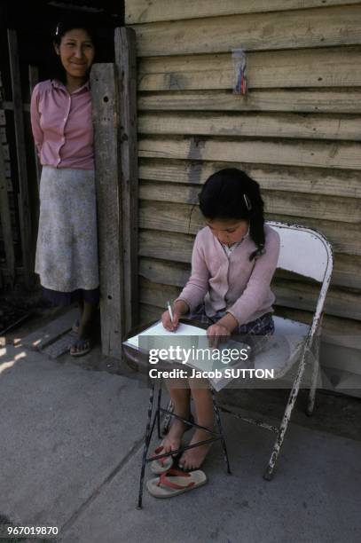 Une jeune fille faisant ses devoirs scolaires devant sa maison du bidonville de Santiago le 19 janvier 1984, Chili.