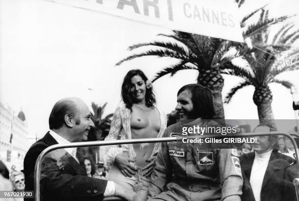 Actrice Edy Williams posant nue avec les pilotes automobile Juan Manuel Fangio et Emerson Fittipaldi à Cannes, le 19 mai 1974.