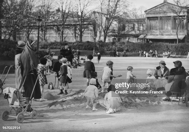 Dans un jardin parisien, des enfants jouent dans un bac à sable sous le soleil printannier, à Paris, France le 21 mars 1935.