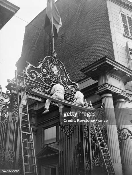 Ouvriers occupés à repeindre la grande porte d'entrée du ministère de l'Intérieur, à Paris, France le 25 septembre 1934.