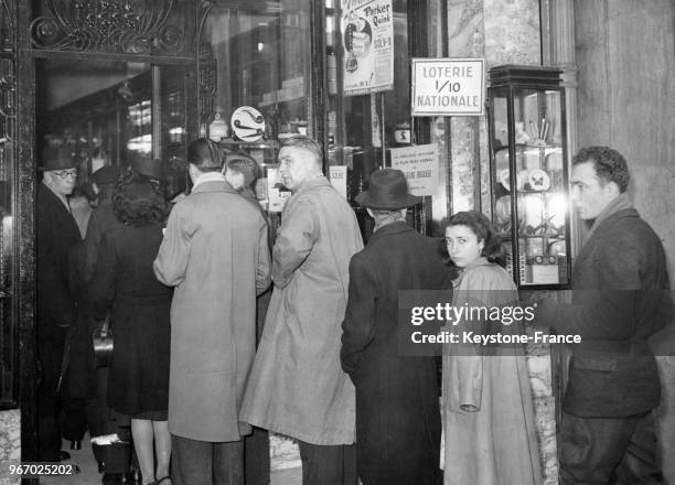 On fait la queue dans un bureau de tabac, en prévision de l'augmentation prochaine des tabacs et cigarettes, à Paris, France, le 22 décembre 1947.