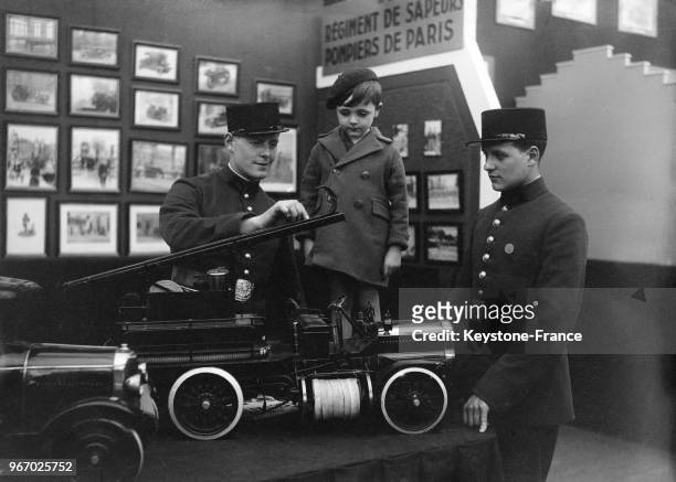 Un pompier explique à un garçon le fonctionnement d'une échelle, à Paris, France le 29 juin 1934.