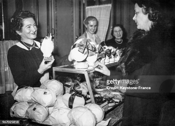 Commerçante présentant à une cliente un oeuf en chocolat et sa poule pour Pâques à Paris, France, le 27 mars 1948.
