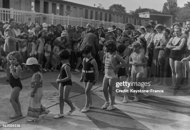 Les petites filles défilent en maillot de bain devant le public à la piscine Molitor à Paris, France le 13 juin 1934.