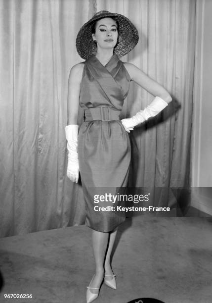 Mannequin présentant le modèle 'Flash' de Christian Dior de la Collection Printemps/Eté 1959: un ensemble de shantung rouge avec une robe sans...