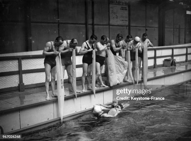 Un nageur fait la démonstration d'un nouvel équipement de nage mis au point par le professeur Chabel à la piscine Champerret-Danton, devant une...