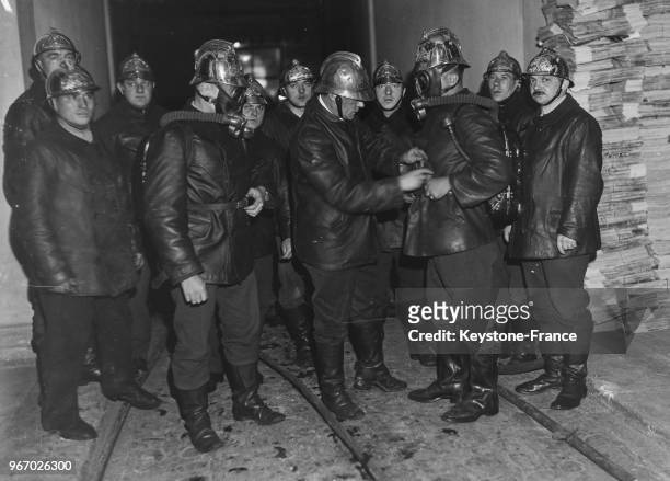 Des pompiers, munis de masques à gaz, s'apprêtent à pénétrer dans la salle du 'Journal', à Paris, France le 16 octobre 1934.