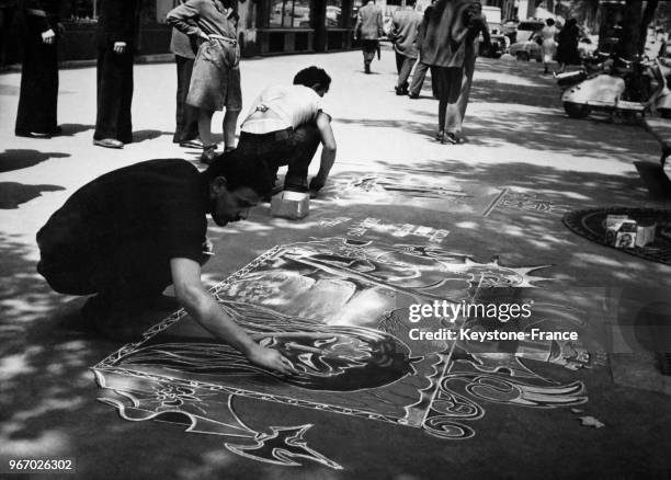 Ces deux jeunes artistes des Beaux-Arts peignent des tableaux sur le trottoir, à Paris, France le 24 juin 1957.