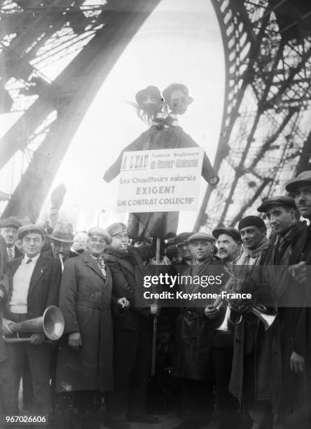 Des chauffeurs de taxi, porteurs de pancarte, manifestent au pied de la Tour Eiffel, à Paris, France le 20 février 1934.