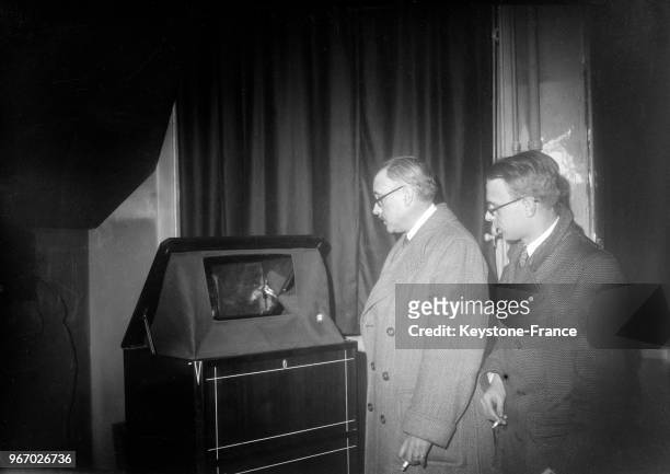 Deux hommes regardent la première émission télévisée retransmise sur un poste de télévision installé rue de Grenelle, à Paris, France le 27 avril...