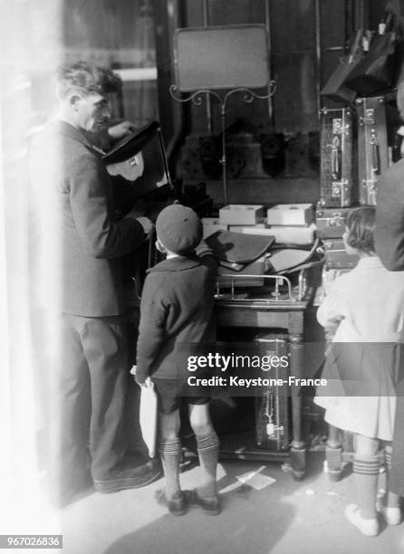 Un jeune écolier qui fait ses achats tout seul chez un maroquinier pour la rentrée scolaire, à Paris, France le 28 septembre 1933.