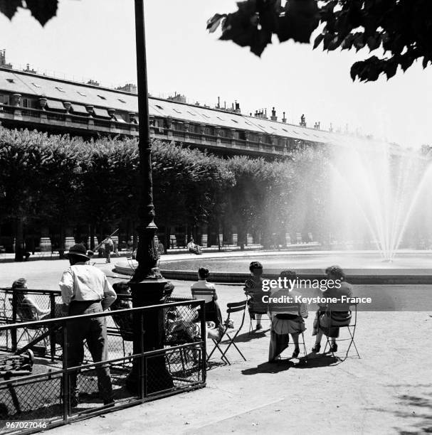 Repos au soleil au bord du bassin dans le jardin du Palais Royal à Paris, France le 21 juillet 1953.