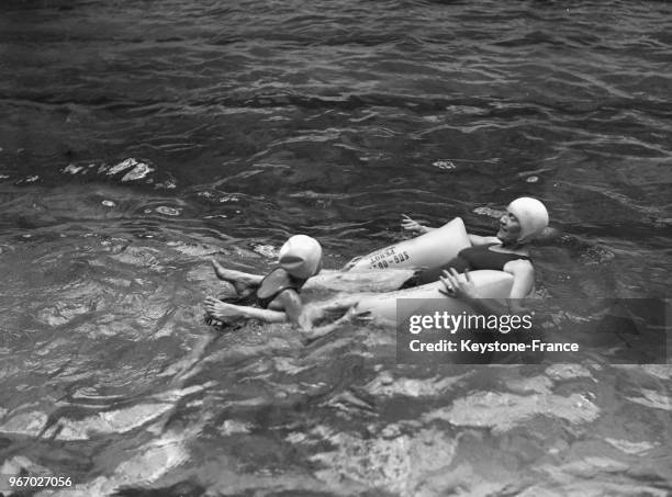 Deux nageurs font une démonstration d'un nouvel équipement mis au point par le professeur Chabel à la piscine Champerret-Danton le 30 mai 1934 à...