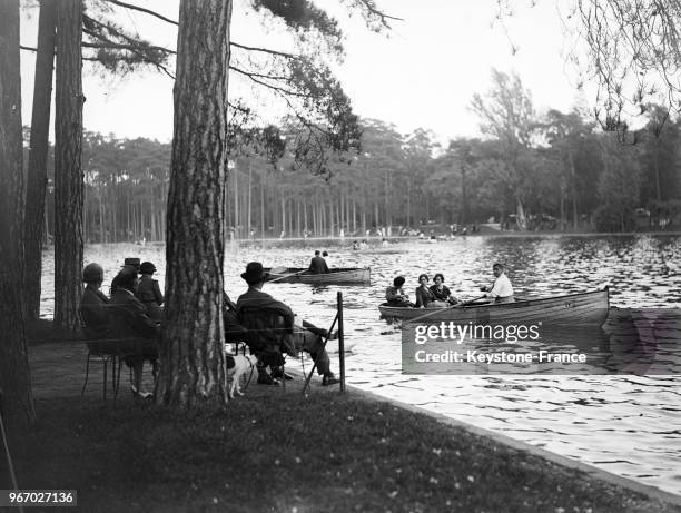 Des Parisiens assis au bord du lac du Bois de Boulogne regardent les barques naviguer en ce dernier jour de vacances, à Paris, France le 29 septembre...