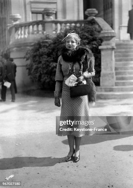 Une femme porte une toilette élégante lors du pesage au Prix du Président de la République à l'hippodrome dAuteuil le 16 avril 1933 à Paris, France.