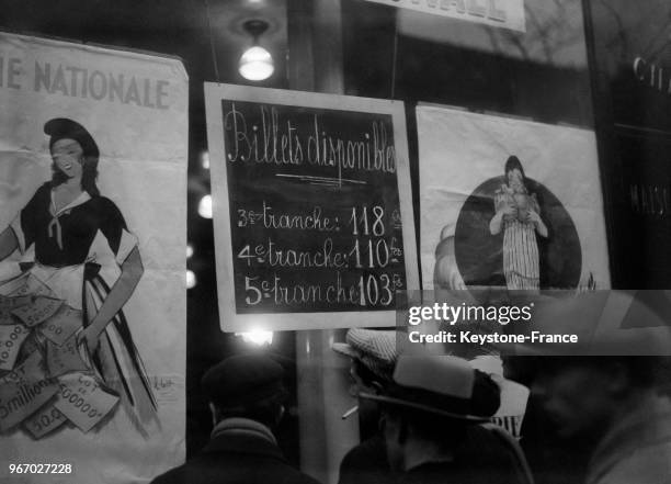La foule devant une banque regarde la côte des billets de la Loterie nationale, à Paris, France le 24 novembre 1933.