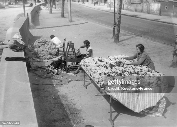 Matelassière au travail sur le trottoir, à Paris, France le 14 avril 1934.