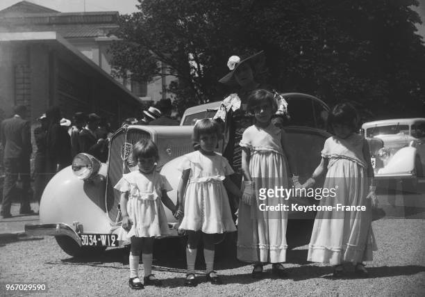 Des enfants photographiés devant une voiture, à Paris, France le 28 juin 1935.