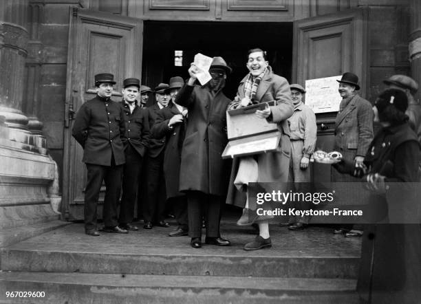 Un gagnant de la Loterie nationale portant un masque sort du Pavillon Flore après avoir encaissé son billet, à Paris, France le 20 décembre 1933.