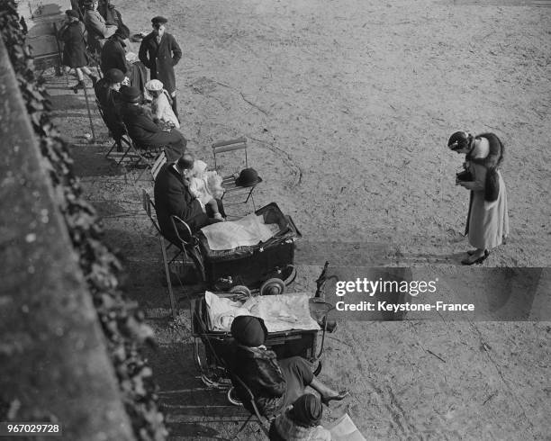 Aux jardin des Tuileries, les parents sortent leurs enfants pour profiter du soleil, à Paris, France le 18 février 1935.