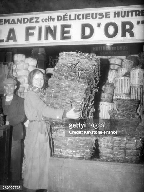 Employée installant un gros arrivage de bourriches d'huîtres aux Halles à Paris, France, le 22 décembre 1934.