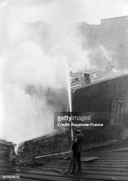 Pompier combattant l'incendie d'une fabrique de jouets rue de Turenne à Paris, France le 26 décembre 1933.