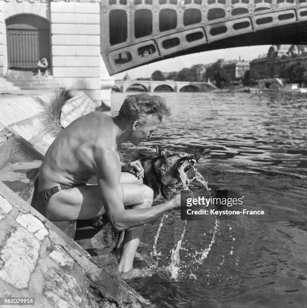 Un homme en maillot de bain et son chien se mouillent dans la Seine, à Paris, France le 27 juillet 1956.