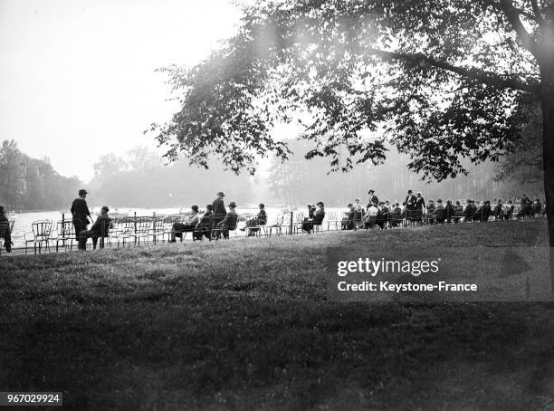 Des Parisiens assis au bord du lac du Bois de Boulogne en ce dernier jour de vacances, à Paris, France le 29 septembre 1934.