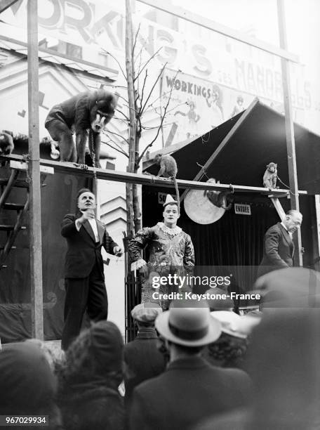 Des singes invitent les passants à visiter une ménagerie à la Foire du Trône à Paris, France le 20 avril 1935.