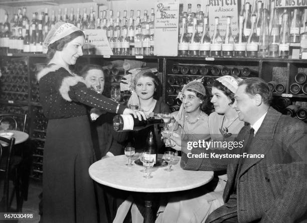 Une catherinette versant à boire à ses camarades, à Paris, France le 25 novembre 1933.