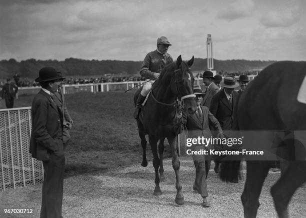 Le gagnant du prix Noailles rentre au pesage après sa victoire à l'hippodrome de Longchamp, à Paris, France le 20 mai 1934.