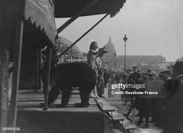 Un cow-boy et une danseuse, accompagnés d'un ours, invitent les passants à entrer dans leur cirque, à Paris, France le 28 mai 1935.