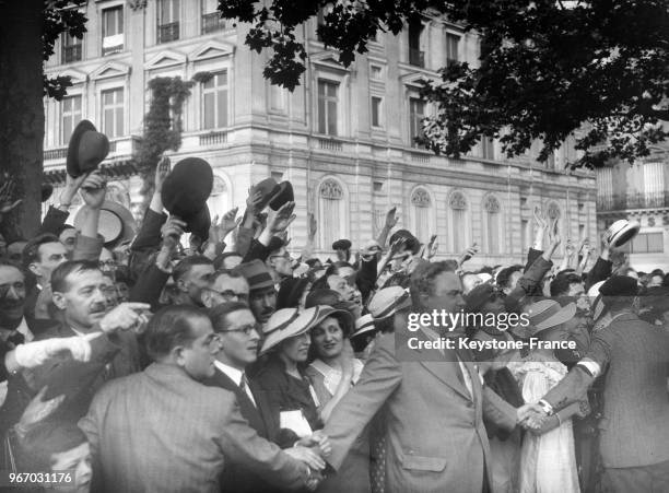 Les partisans du groupement politique 'Front national' qui défilent avenue des Champs-Elysées, les saluent à leur passage, à Paris, France le 14...