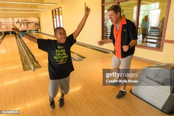 Kevin Rahm and a child celebrate a strike while bowling at Pinstripes during the Big Slick Celebrity Weekend benefitting Children's Mercy Hospital of...