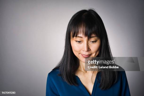 studio portrait of adult japanese woman with long dark hair - mirar hacia abajo fotografías e imágenes de stock
