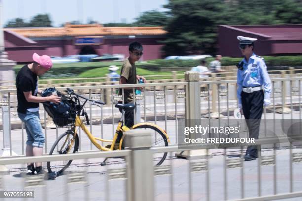 Police officer checks the identity of people in Tiananmen Square on the anniversary of the 1989 crackdown on democracy protestors, in Beijing on June...