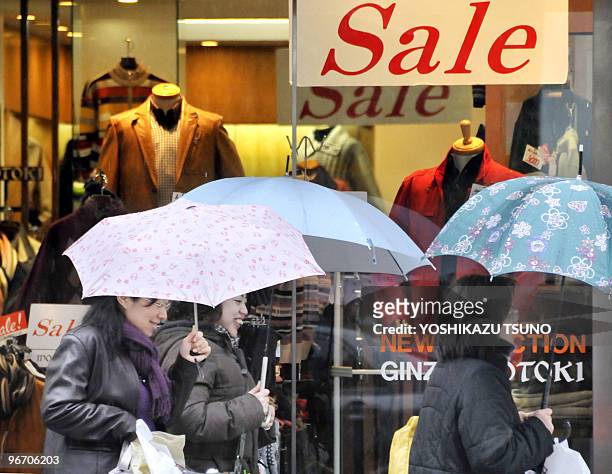 Japan-China-economy-society,FOCUS by Hiroshi Hiyama Shoppers walk past an apparel shop displaying a large "sale" sign in Tokyo on February 15, 2010....