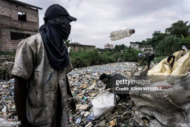 Congolese men collect plastic bottles on the edge of the Kalamu River on May 31, 2018 in Kinshasa. On June 5, 2018 the United Nations mark the World...