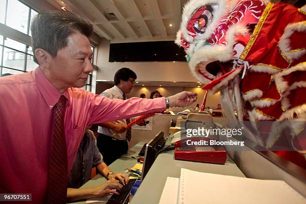 Stock broker interacts with a dragon dance performer during a ceremony for Chinese Lunar New Year on the trading floor of the Philippine Stock...