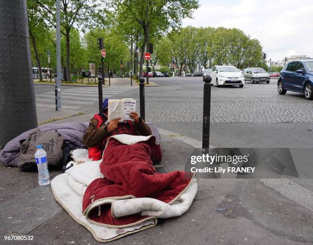 Homme SDF installé sur le trottoir du Boulevard de l'Hôpital lisant un livre, 17 avril 2017, Paris 13e, France.