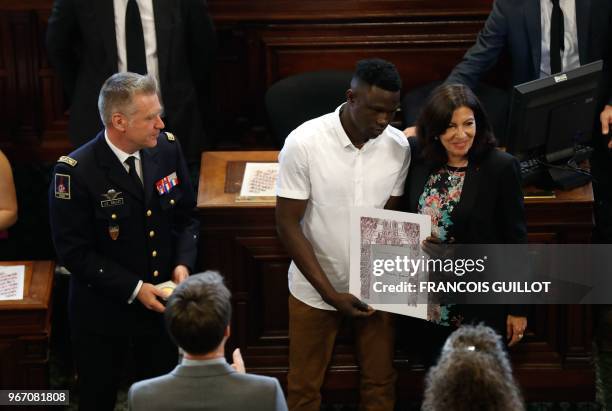Malian migrant Mamoudou "Spider-Man" Gassama is awarded with the city's Grand Vermeil medal by Paris' mayor Anne Hidalgo , as the chief of the Paris'...
