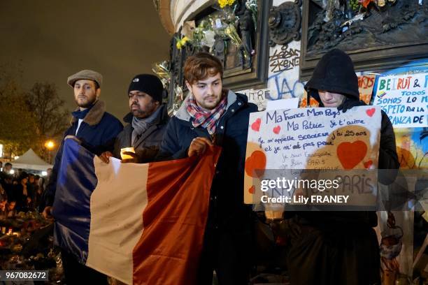 Groupe de jeunes hommes brandissant un drapeau français et tenant une pancarte en hommage aux victimes des attentats place de la République, le 18...