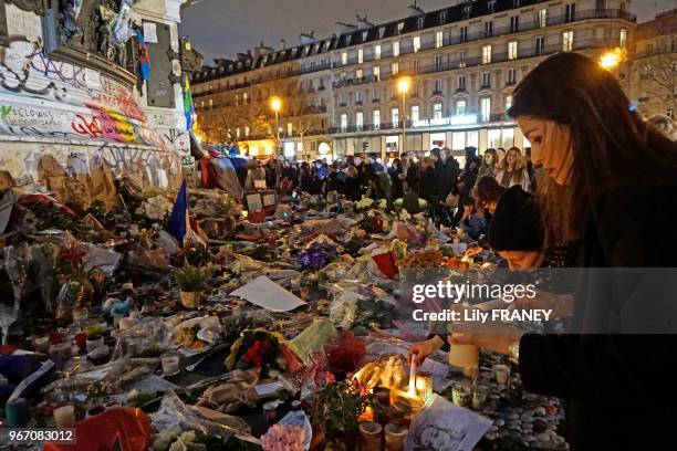 Jeune fille parmi la foule allumant une bougie en hommage aux victimes des attentats, place de la République, le 18 novembre 2015, Paris, France.