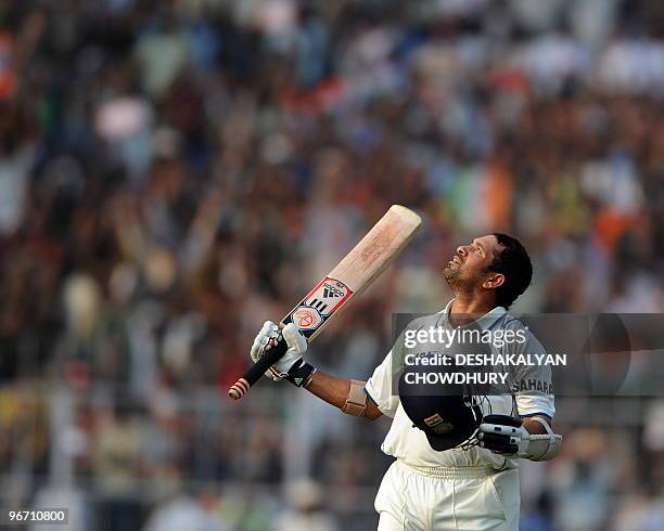 Indian cricketer Sachin Tendulkar raises his bat in celebration of scoring a century during the second day of the second Test match between India and...