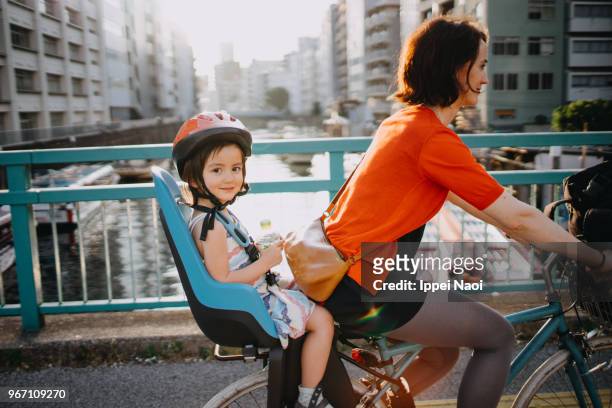mother riding a bicycle with a toddler girl in urban city, tokyo - fille sport photos et images de collection