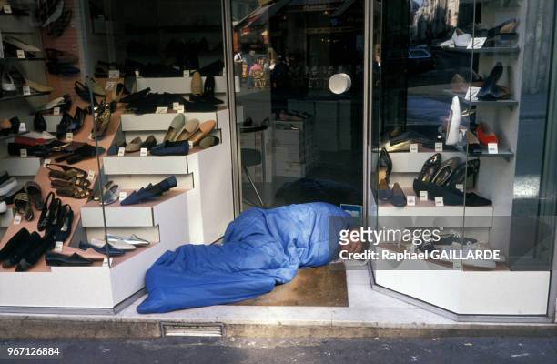 Sans abri dormant contre la vitrine d'un magasin lors d'une vague de froid le 16 décembre 1991 à Paris, France.
