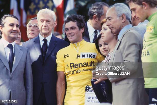 Bernard Hinault revêtu du maillot jaune entouré des hommes politiques Jean-Pierre Soisson et Maurice Couve de Murville lors de sa victoire dans le...